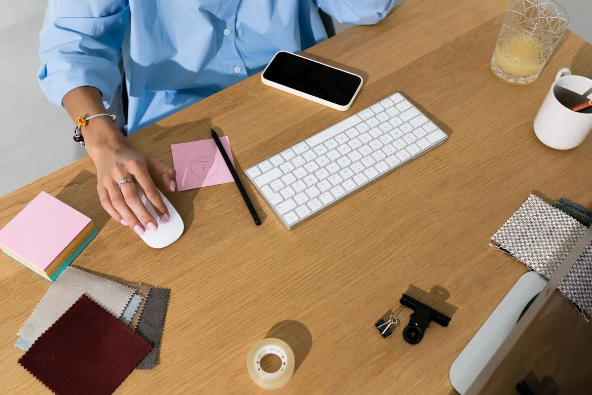 A designer's desk covered in fabric swatches and colour samples, with a laptop pushed to one side.